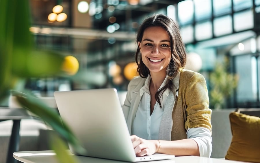 employee happily working with laptop, wearing corporate clothes, focused on subject blurred background, in an office setup